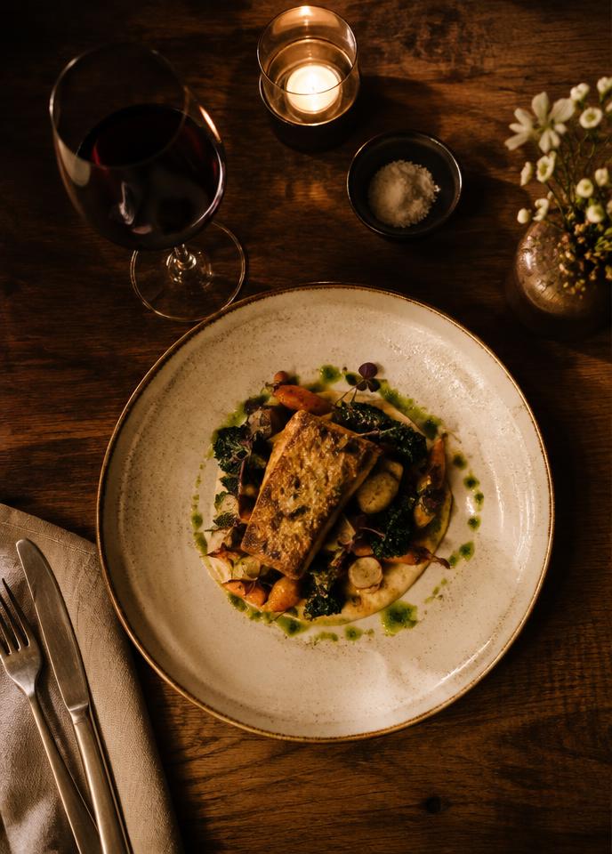 Plated dish and red wine on a candlelit restaurant table